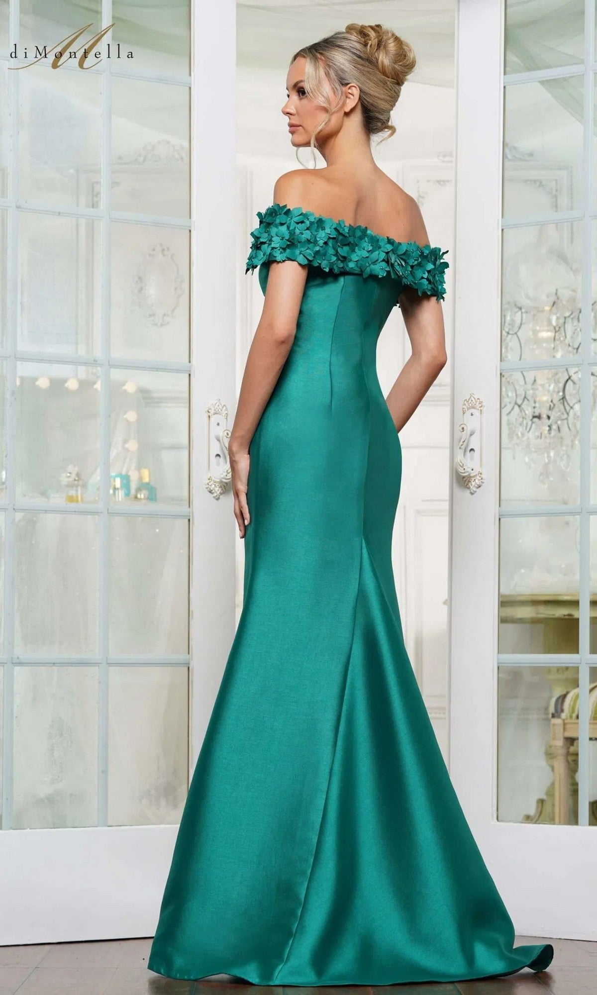 A woman in the Rina Di Montella RD3254 long formal dress stands facing double glass doors in an elegant room.